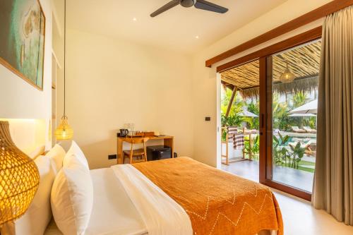 a bedroom with a bed and a door to a patio at Uryah Hotel Lombok in Selong Belanak