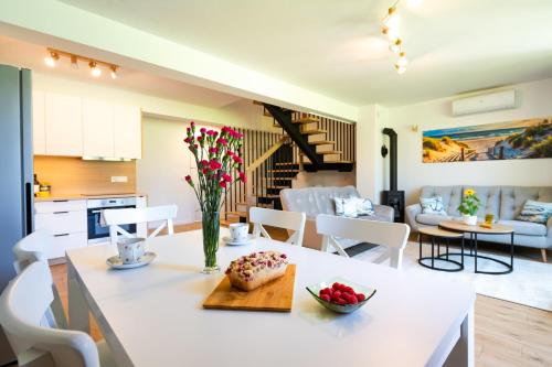 a kitchen and living room with a table with a vase of flowers at Ostoja Lubiatowo in Lubiatowo