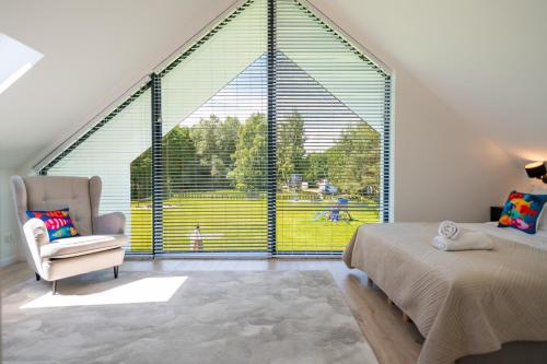 a bedroom with a large window with a bed and a chair at Ostoja Lubiatowo in Lubiatowo