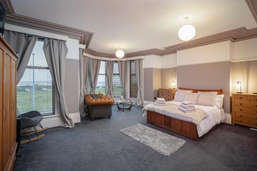 a bedroom with a bed and a chair and windows at Comfortable family home with amazing Seaviews in Fleetwood