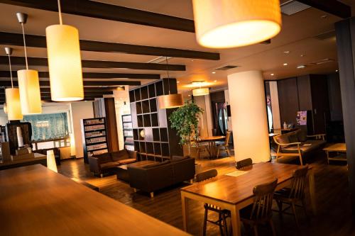 a lobby with tables and chairs and lights at Ooedo Onsen Monogatari Hotel Reoma no Mori in Marugame