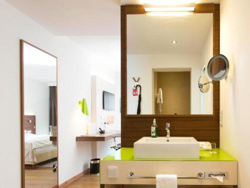a bathroom with a sink and a mirror at Wolfsburg Sandkamp Hotel by Belvilla in Wolfsburg