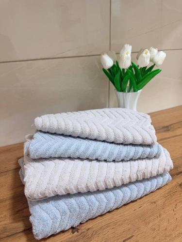 a stack of towels on a table with a vase of flowers at Семейные номера с ванной, кухней в Яхт Виллидж Чолпон-Ата in Cholpon-Ata