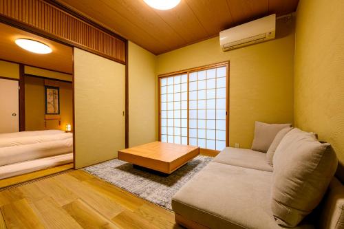 a room with a couch and a table and a window at Yufuin Ryokan Yufumomiji in Yufu