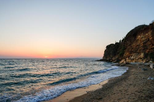 a beach with the sun setting over the ocean at Pachynammos Studios & Apartments in Kypseli