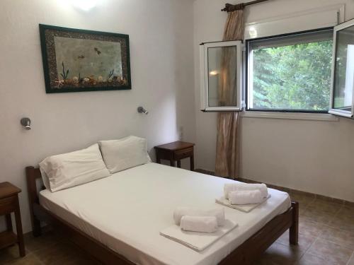 a bedroom with a white bed with two towels on it at Aidonofolies in Koukounaries