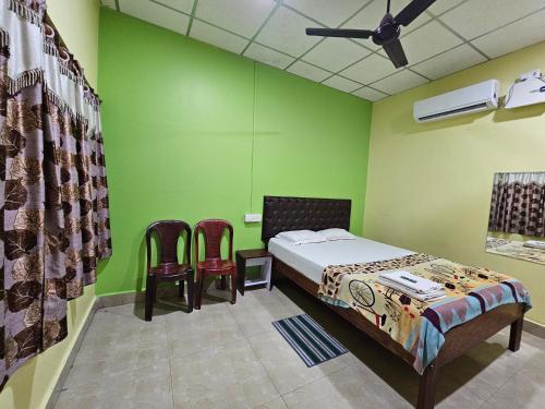 a bedroom with green walls and a bed and two chairs at Harmony - Havelock Island in Havelock Island