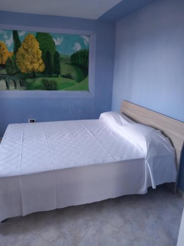 a bedroom with a white bed with a painting on the wall at Casa vacanze Melania in Cupra Marittima
