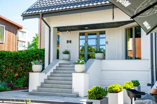 a white house with stairs and potted plants at Vila Ieva in Palanga