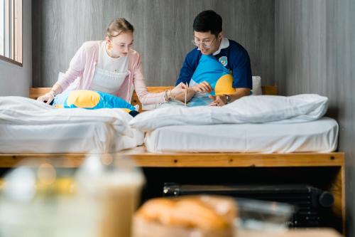 a man and a woman sitting on beds at BESTIE - Doyanen Hotels in Osaka