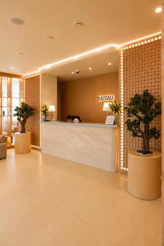 a hotel lobby with a hair salon with two potted trees at Baitau Hotel Aktobe in Aktobe