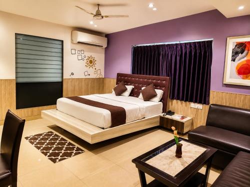 a bedroom with a bed and a couch and a table at Pentagon Next Bhubaneswar in Bhubaneshwar