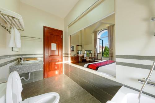 a bathroom with a toilet and a bed in a room at Maro Boutique Villa in Da Lat