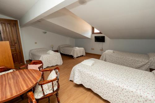 a room with three beds and a table and chairs at posada trastamara in Piedralaves