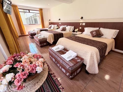 a hotel room with two beds and flowers in it at Boutique Inka Hotel in Ollantaytambo