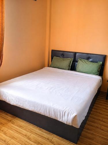 a bed with white sheets and green pillows on it at Perfect View Homestay in Cherrapunji