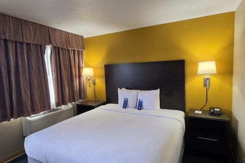 a large white bed in a hotel room with yellow walls at Howard Johnson by Wyndham Odessa TX in Odessa