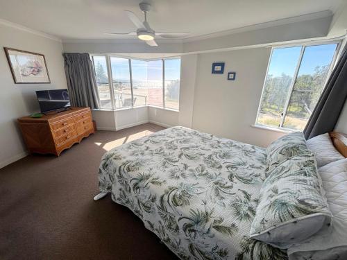 a bedroom with a bed and a dresser and windows at Ocean Shores Apartment 15 - Bring your own linen. in South West Rocks