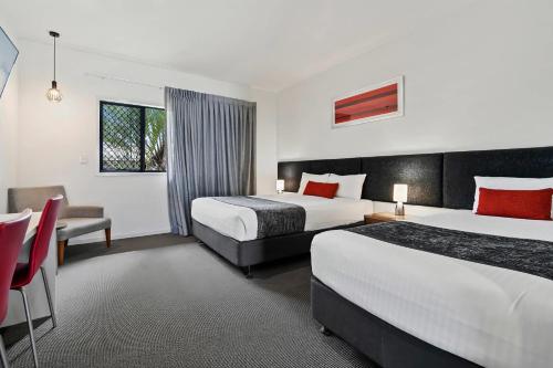 a hotel room with two beds and a table and chairs at Quality Resort Parkhurst in Rockhampton