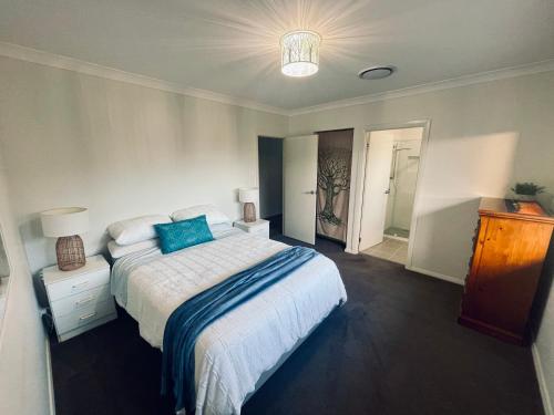 a bedroom with a bed with a blue pillow on it at Guest house Que Sera in Cooranbong