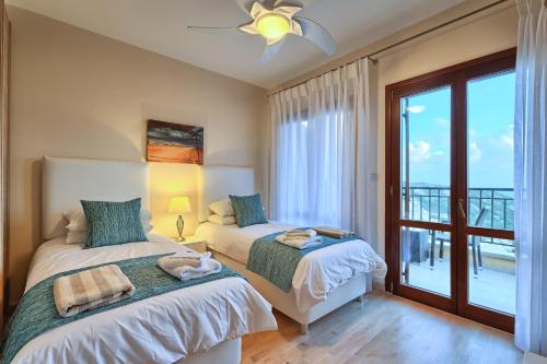 a bedroom with two beds and a balcony at 2 bedroom Villa Iremos with private pool and sea views, Aphrodite Hills Resort in Kouklia