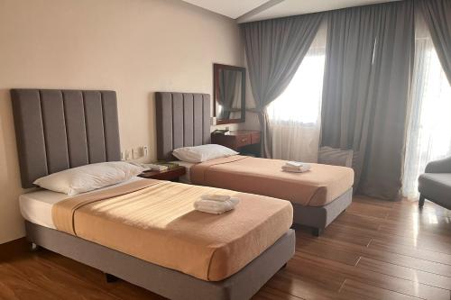 a hotel room with two beds and a couch at NSCC Stella Maris Hotel & Convention Center in Cabugao