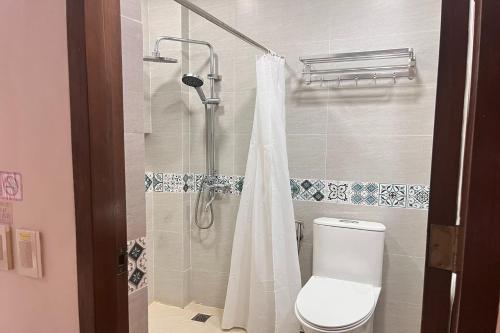 a bathroom with a shower with a toilet and a shower curtain at NSCC Stella Maris Hotel & Convention Center in Cabugao