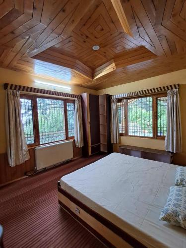 a bedroom with a large bed with wooden ceilings and windows at Shantiloka - Private 1BHK Homestay in Kulu