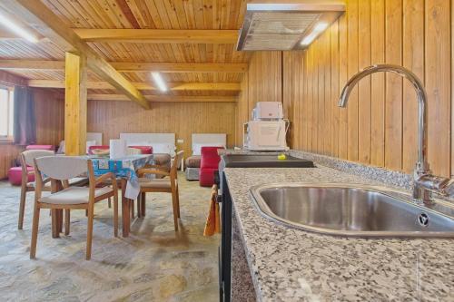 a kitchen with a sink and a table with chairs at Vivienda Jardin in Monforte de Lemos
