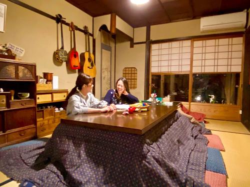 two women sitting at a table in a room at Guesthouse Kioto in Kyoto