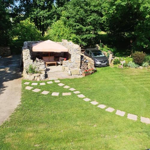 a stone house with a table and a car in a yard at Dworek Marmis - idealny dla rodzin in Mirsk
