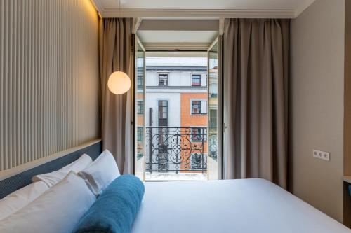 a hotel room with a bed and a balcony at Petit Palace Plaza España in Madrid