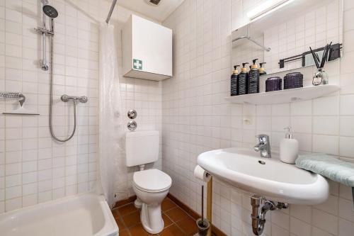 a white bathroom with a toilet and a sink at Apartment Gardenview in Kinsau