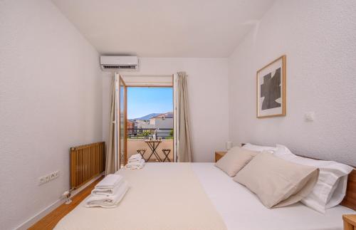 a bedroom with a white bed and a window at Villa Botanica near Split - Heated Pool and Garden in Kučine
