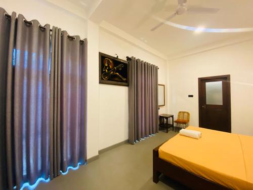 a bedroom with two beds and curtains and a table at Greenbliss Hiriketiya in Dickwella