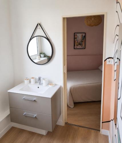 a bathroom with a sink and a mirror and a bed at Le Nid Didier in Saint-Didier-en-Velay