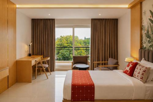a hotel room with a bed and a desk and a window at ORYN-Celebrity Resort, Shamirpet, Hyderabad, Secunderabad, in Shamirpet