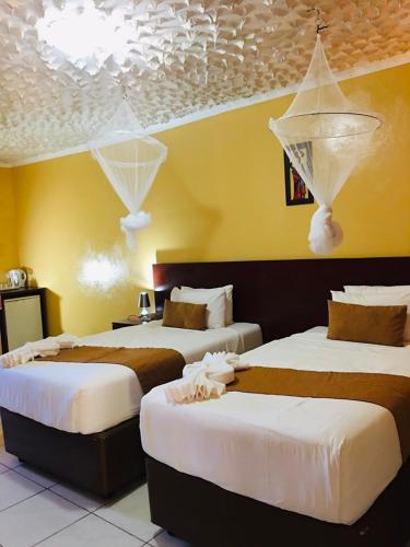 two beds in a room with yellow walls at Nkanga Hotel in Kasane