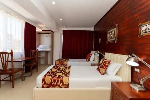 ein Hotelzimmer mit zwei Betten, einem Tisch und einem Schreibtisch in der Unterkunft Hotel Platea in Shkodra