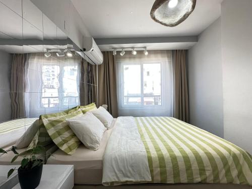 a bedroom with a bed with a striped comforter and two windows at Lüks Konforlu ve merkezi ev in Çiftlikköy