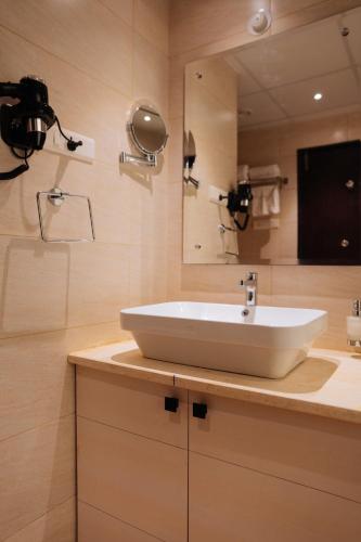 a bathroom with a white sink and a mirror at ORYN-Celebrity Resort, Shamirpet, Hyderabad, Secunderabad, in Shamirpet