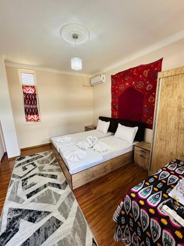 a bedroom with two beds and a rug at Mashhur in Bukhara