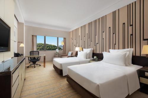 a hotel room with two beds and a television at Grand Pacific Hotel Ningbo in Yuyao