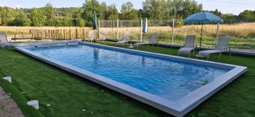 a swimming pool in a yard with chairs and an umbrella at Gîtes le clos du verger avec piscine chauffée commune in Maurens