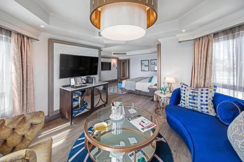 a living room with a blue couch and a bed at Labourdonnais Waterfront Hotel in Port Louis