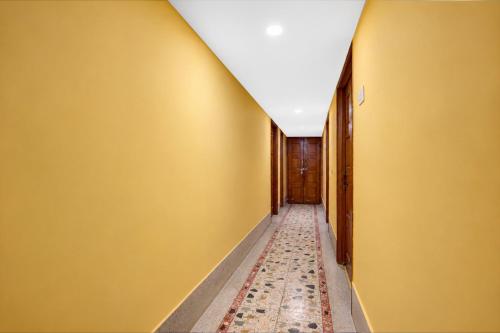 a hallway with yellow walls and a rug at SPOT ON Khedia Inn in Bokāro