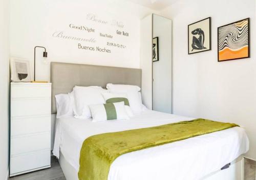 a bedroom with a white bed with a green blanket on it at Apartment Pink Vistalegre in Torrevieja