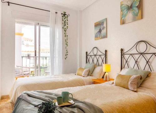 a bedroom with two beds and a window with a view at Bungalow Pink Punta Prima in Alicante