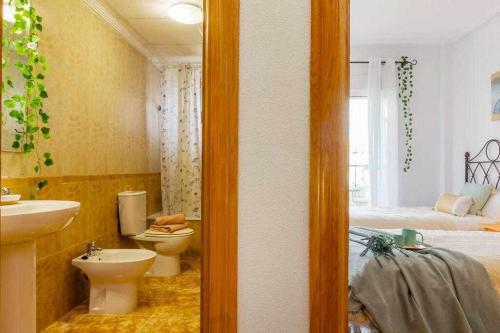 a bathroom with a sink and a toilet and a bed at Bungalow Pink Punta Prima in Alicante