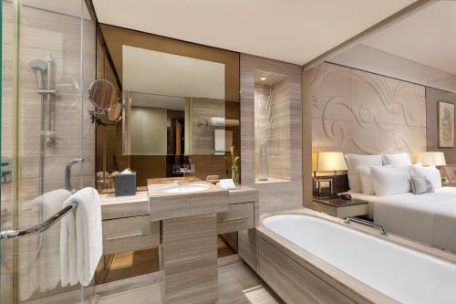 a bathroom with a bed and a bath tub next to a bedroom at Grand Pacific Hotel Ningbo in Yuyao